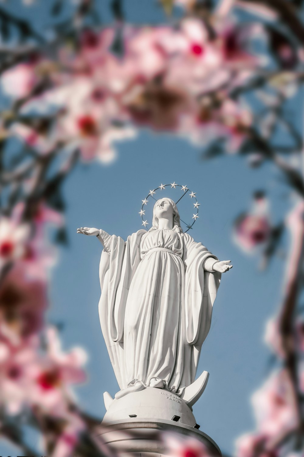 Una estatua de Jesús rodeada de flores rosadas