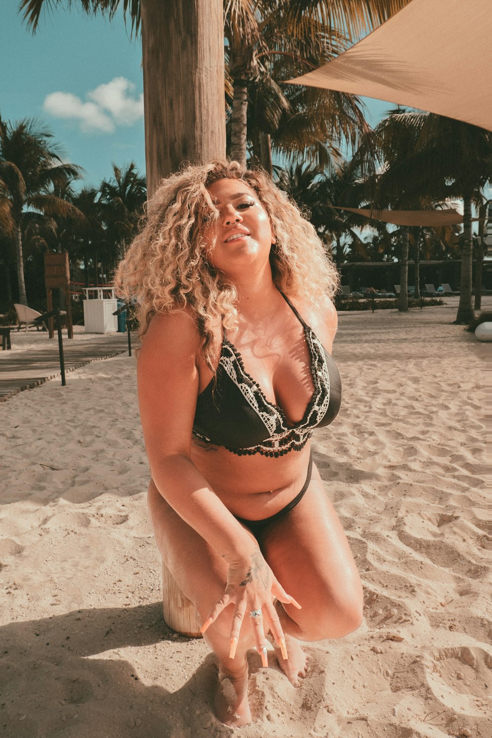 a woman kneeling down on a sandy beach