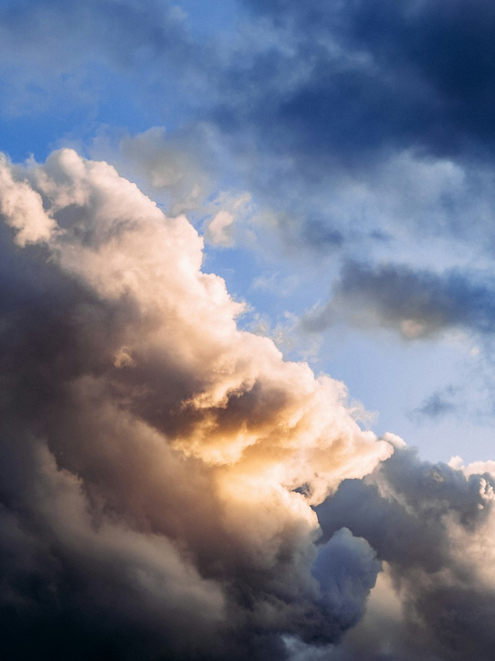 a plane flying through a cloudy blue sky