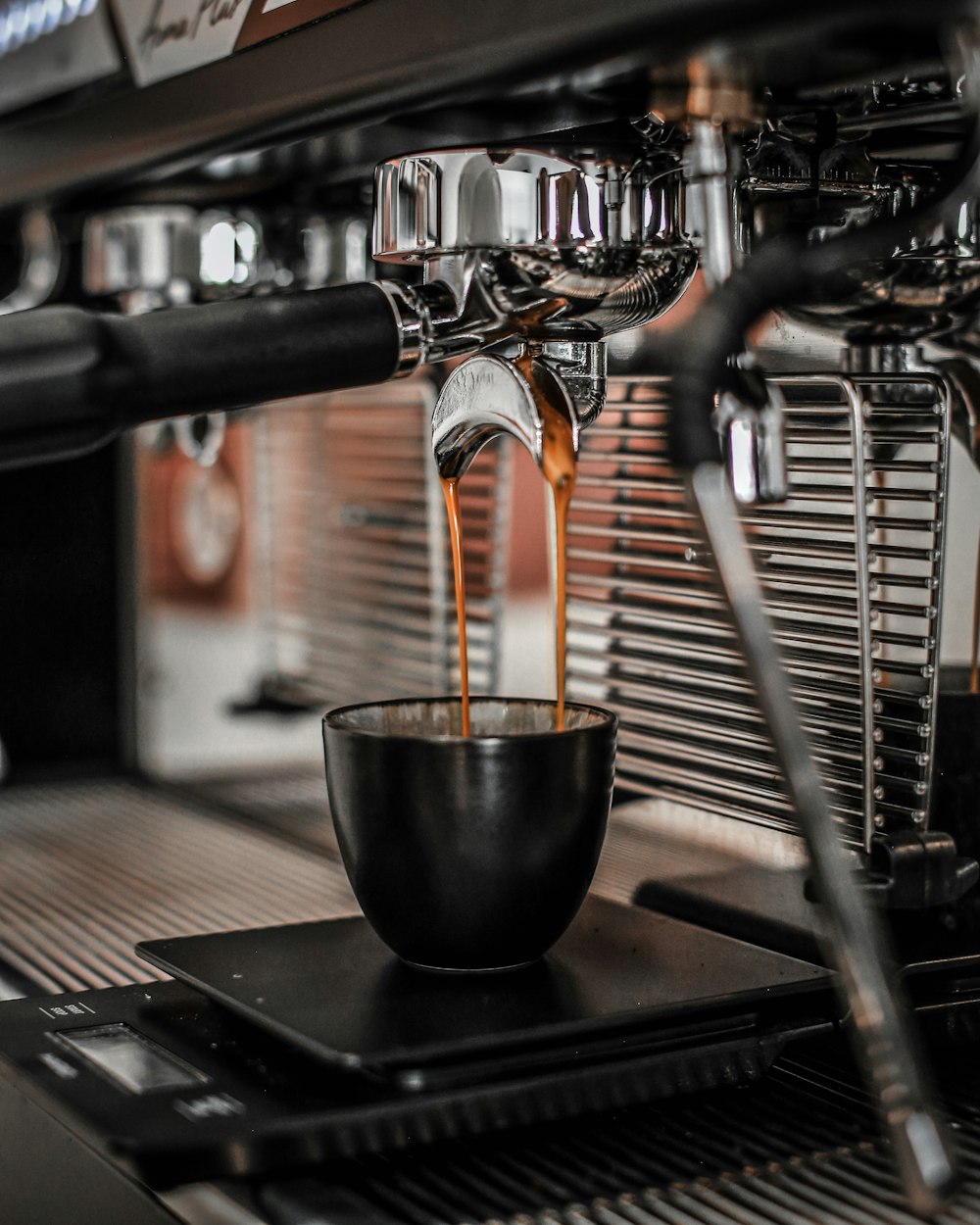 a cup of coffee being poured into a coffee machine