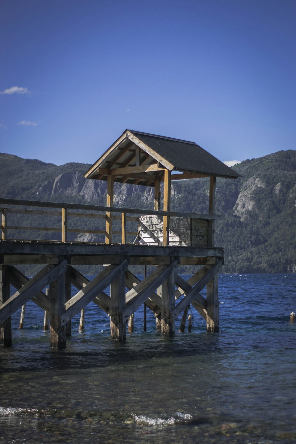 a pier with a boat in the water and mountains in the background