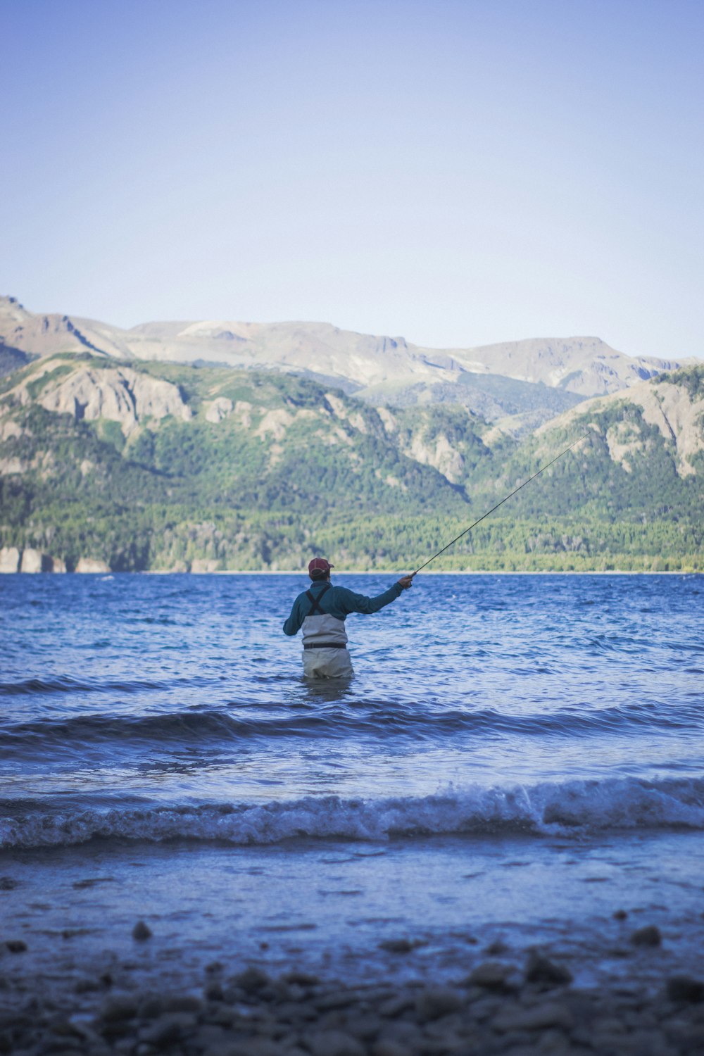 a man in a body of water holding a fishing rod