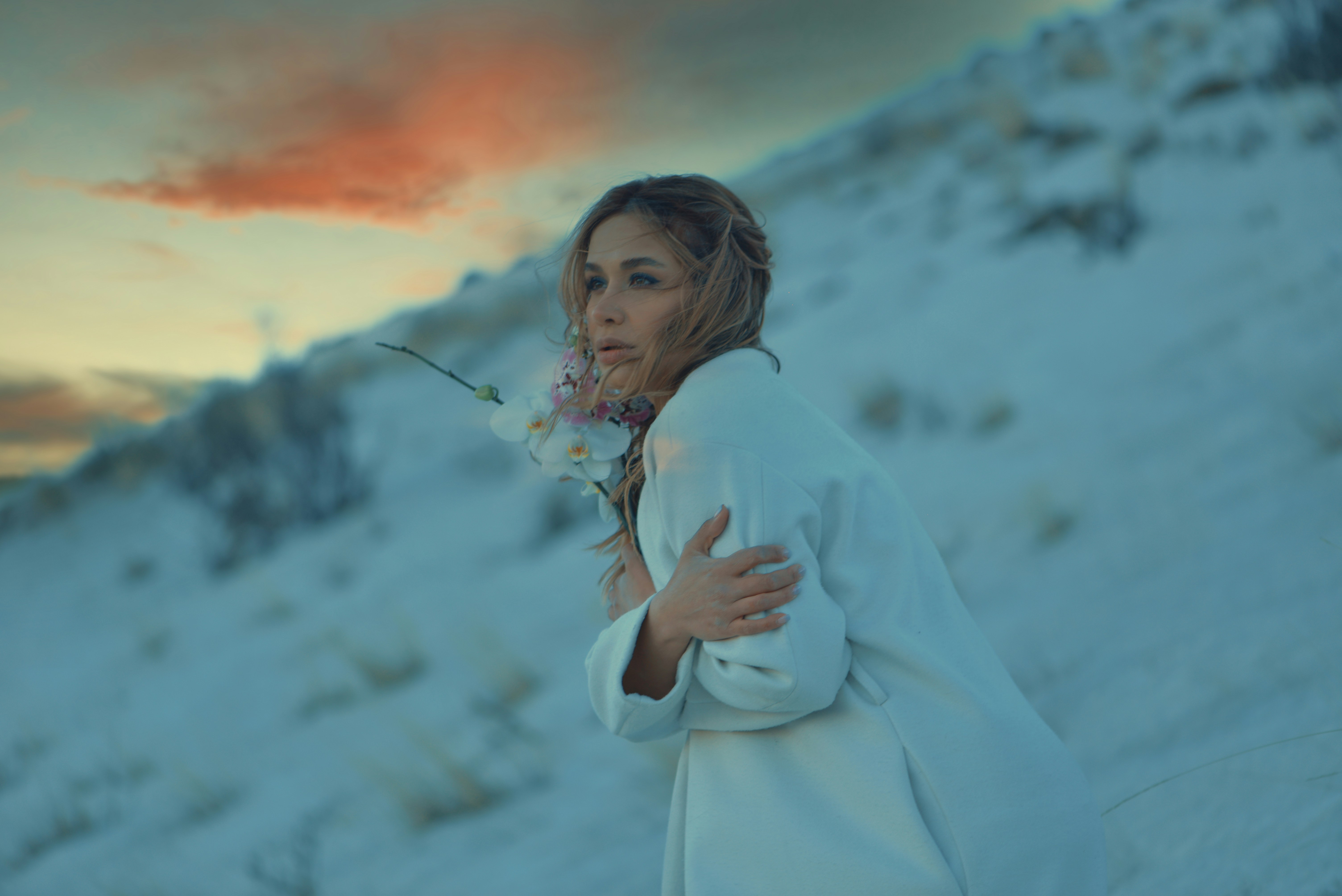 a woman in a white coat holding a flower