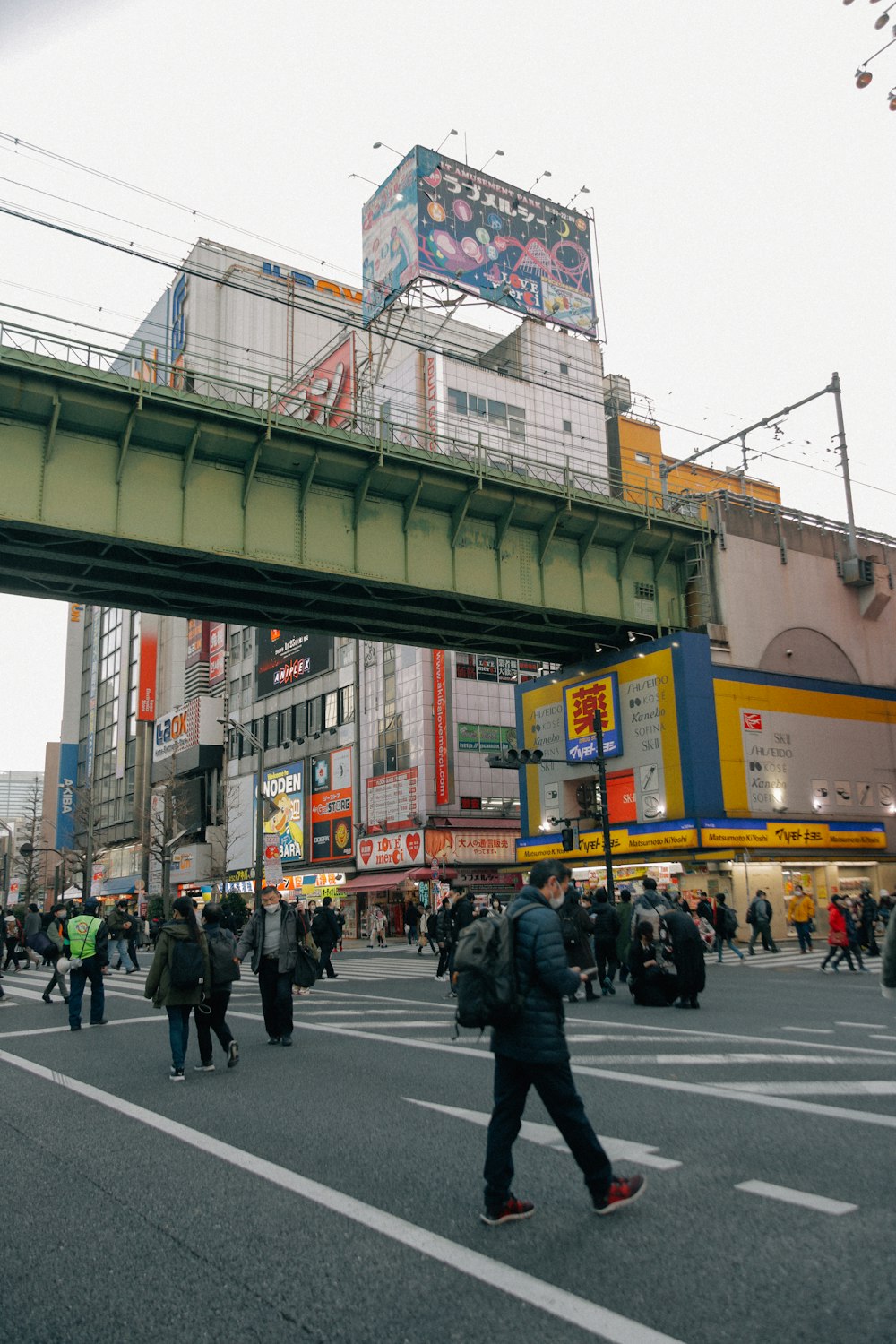 a group of people walking across a street under a bridge