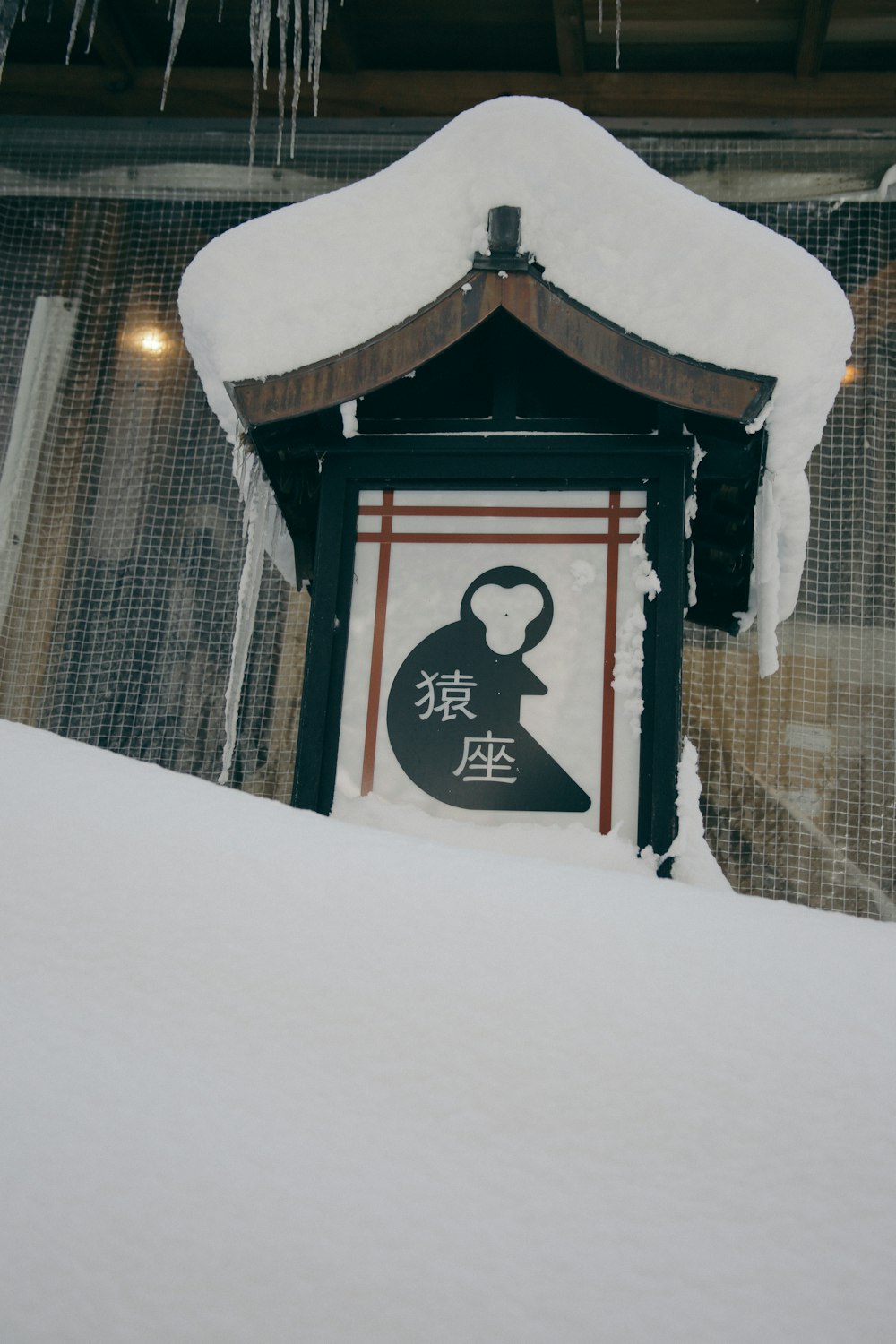 a sign covered in snow with icicles hanging from the roof