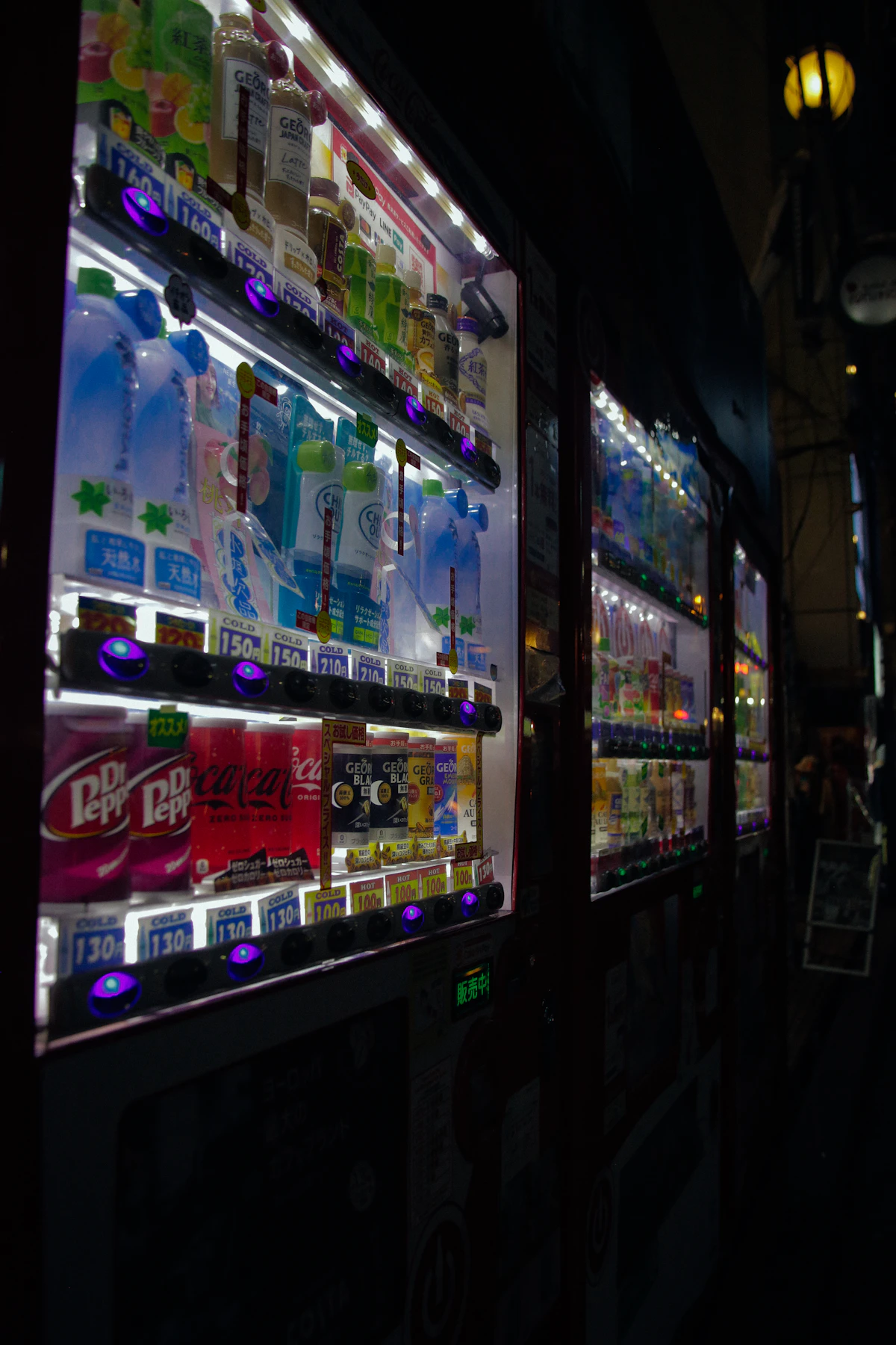 An illuminated Japanese drink vending machine at night