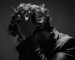 a black and white photo of a man covering his face