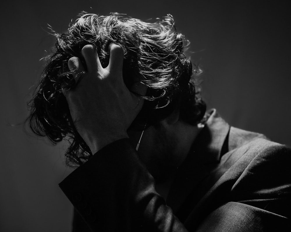 a black and white photo of a man covering his face