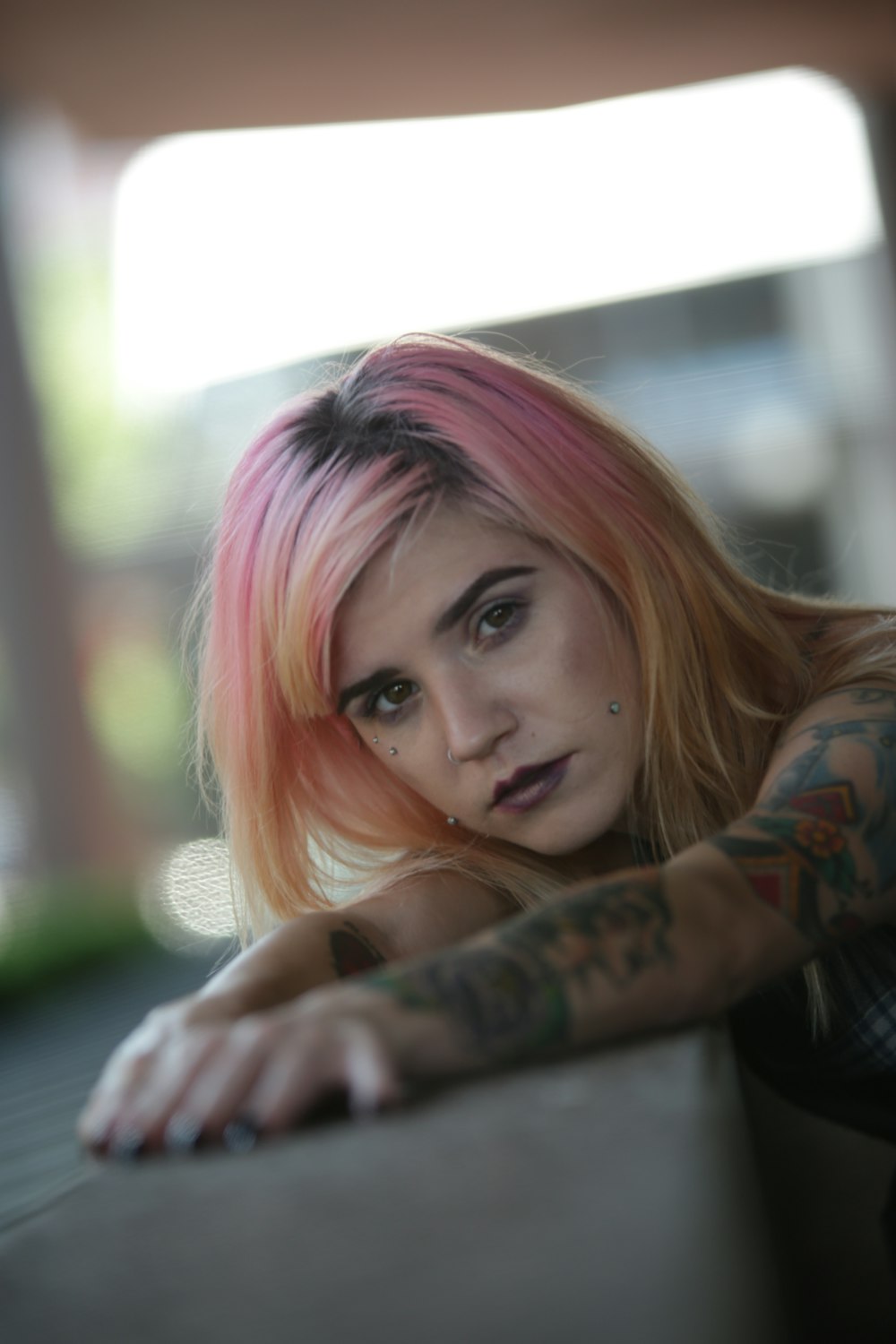 a woman with pink hair leaning on a wall