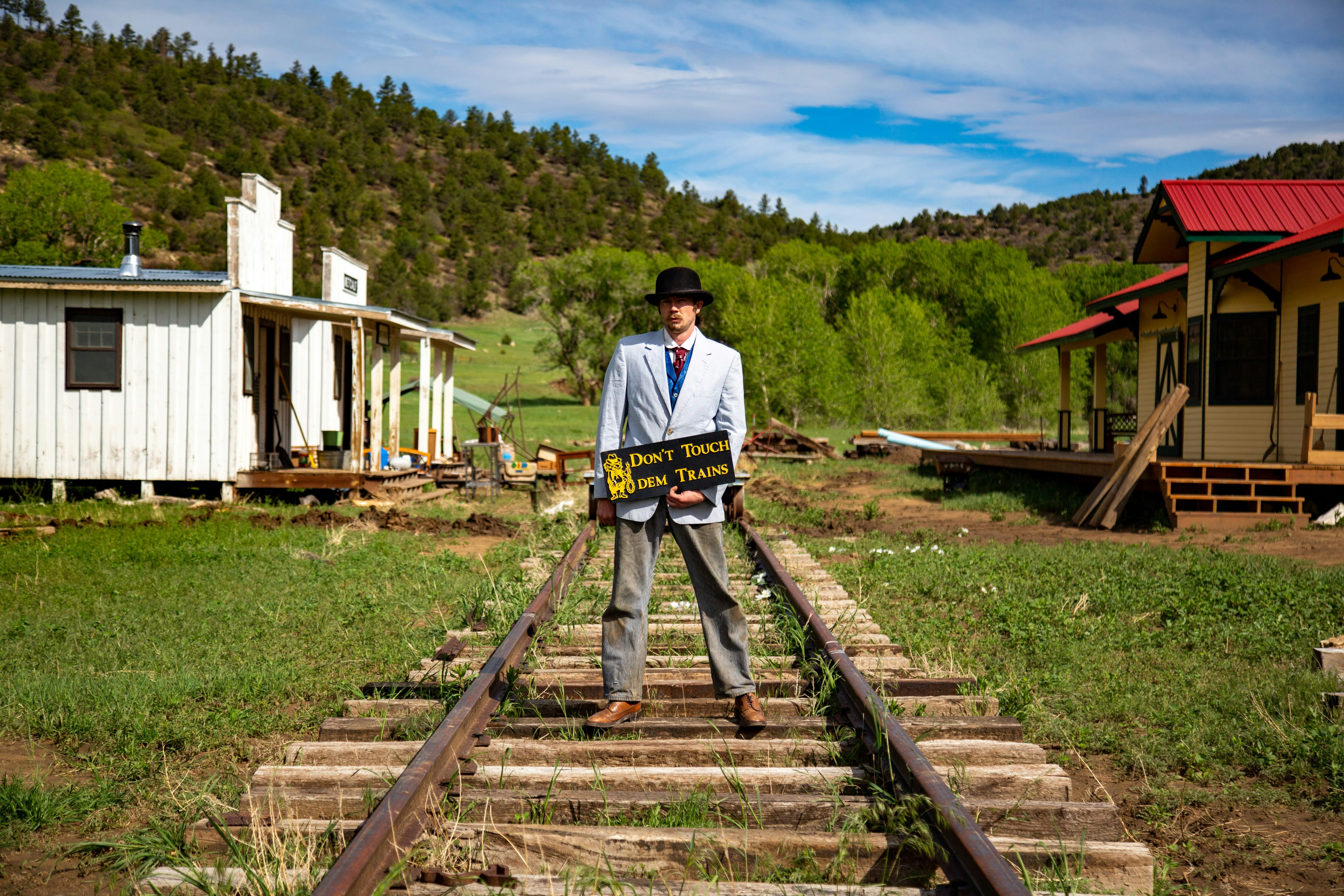 Un hombre parado en una vía de tren sosteniendo un cartel