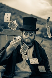 a man wearing a top hat and glasses holding playing cards