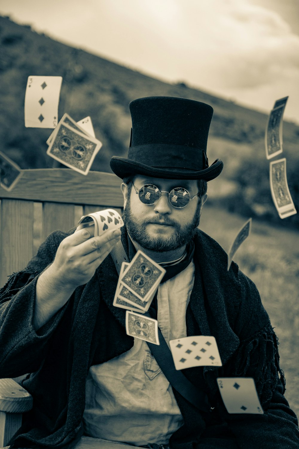 a man wearing a top hat and glasses holding playing cards