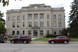 two cars parked in front of a large building