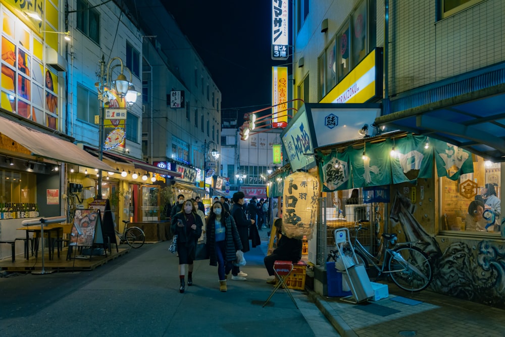 a group of people walking down a street at night