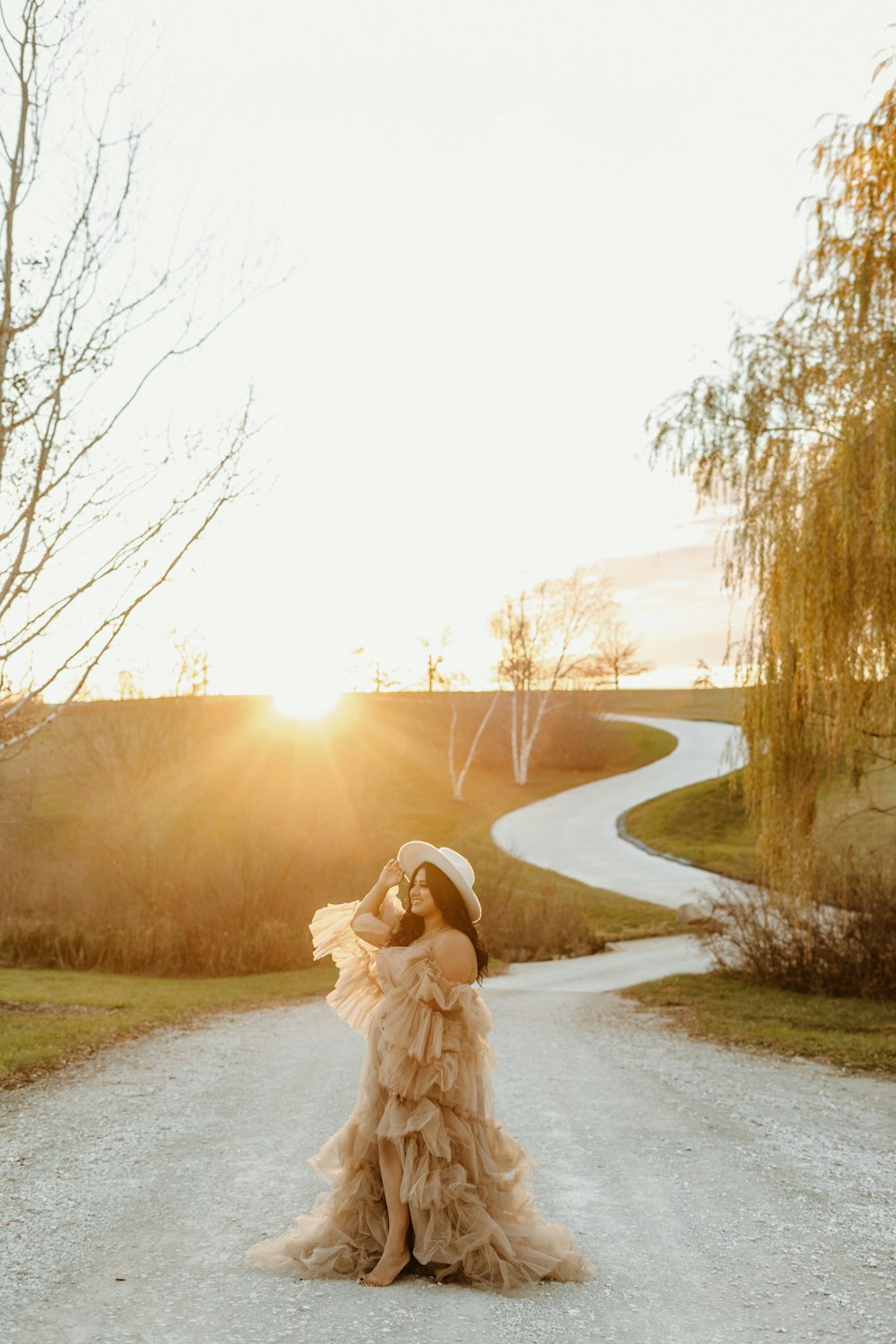 a woman in a dress standing on a dirt road