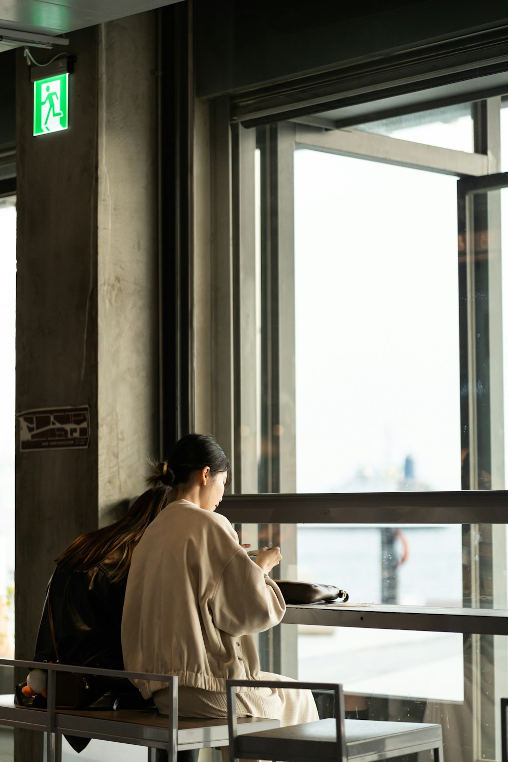 a woman sitting on a bench looking out a window