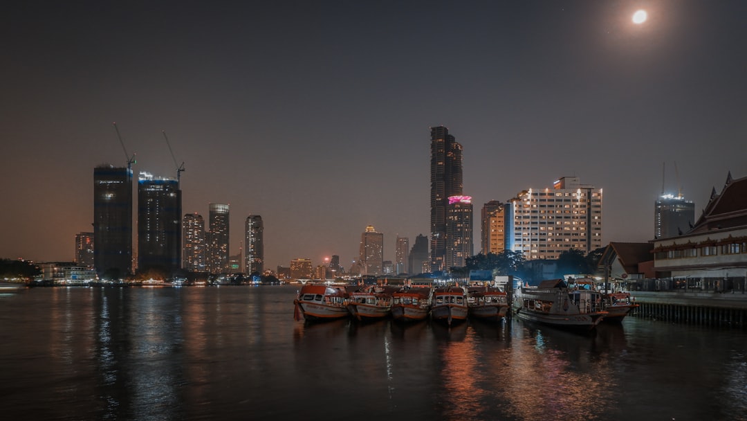 a group of boats floating on top of a body of water, Captured a truly enchanting photo of boats parked along the Chao Ph