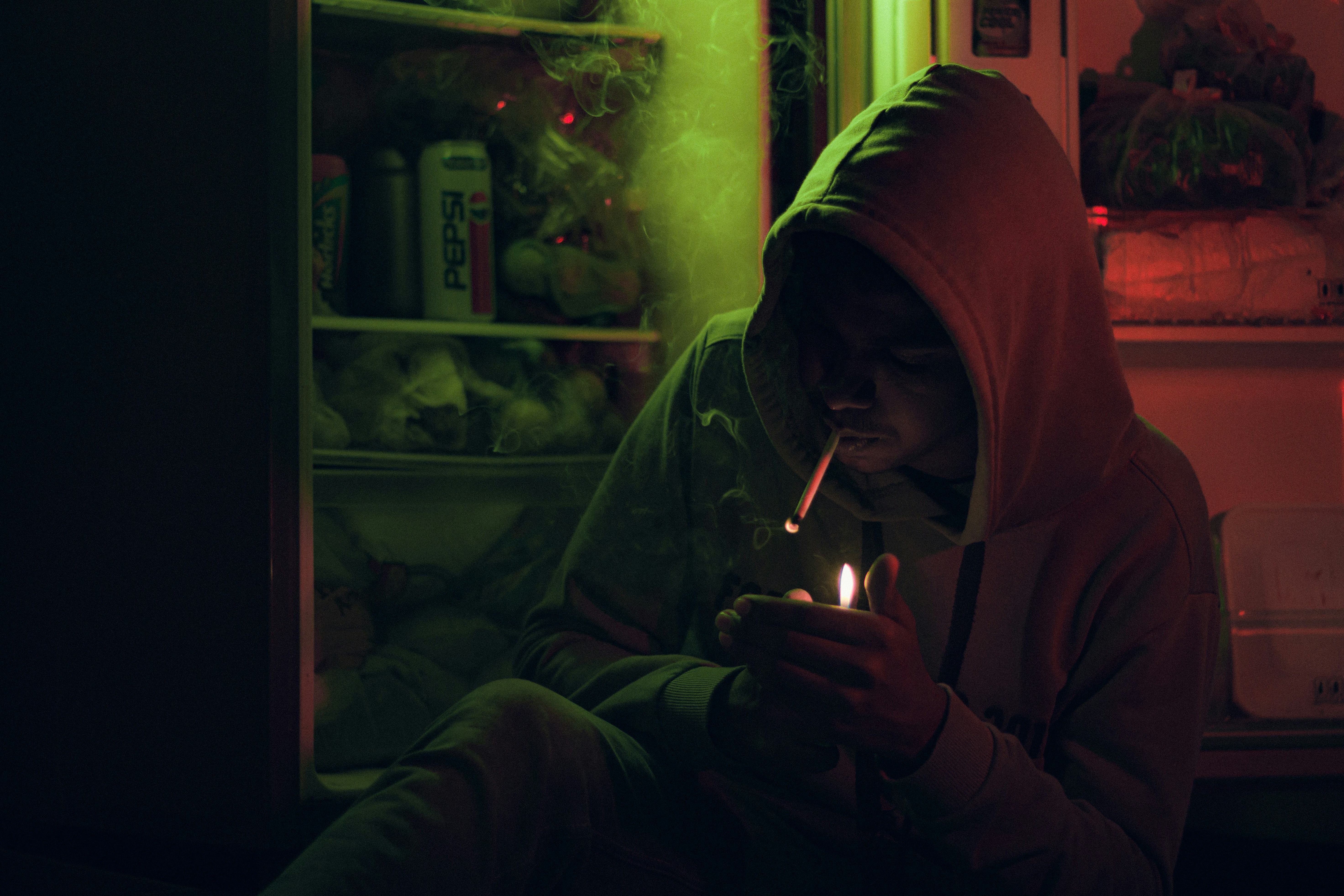 a person sitting in front of a refrigerator holding a lit candle