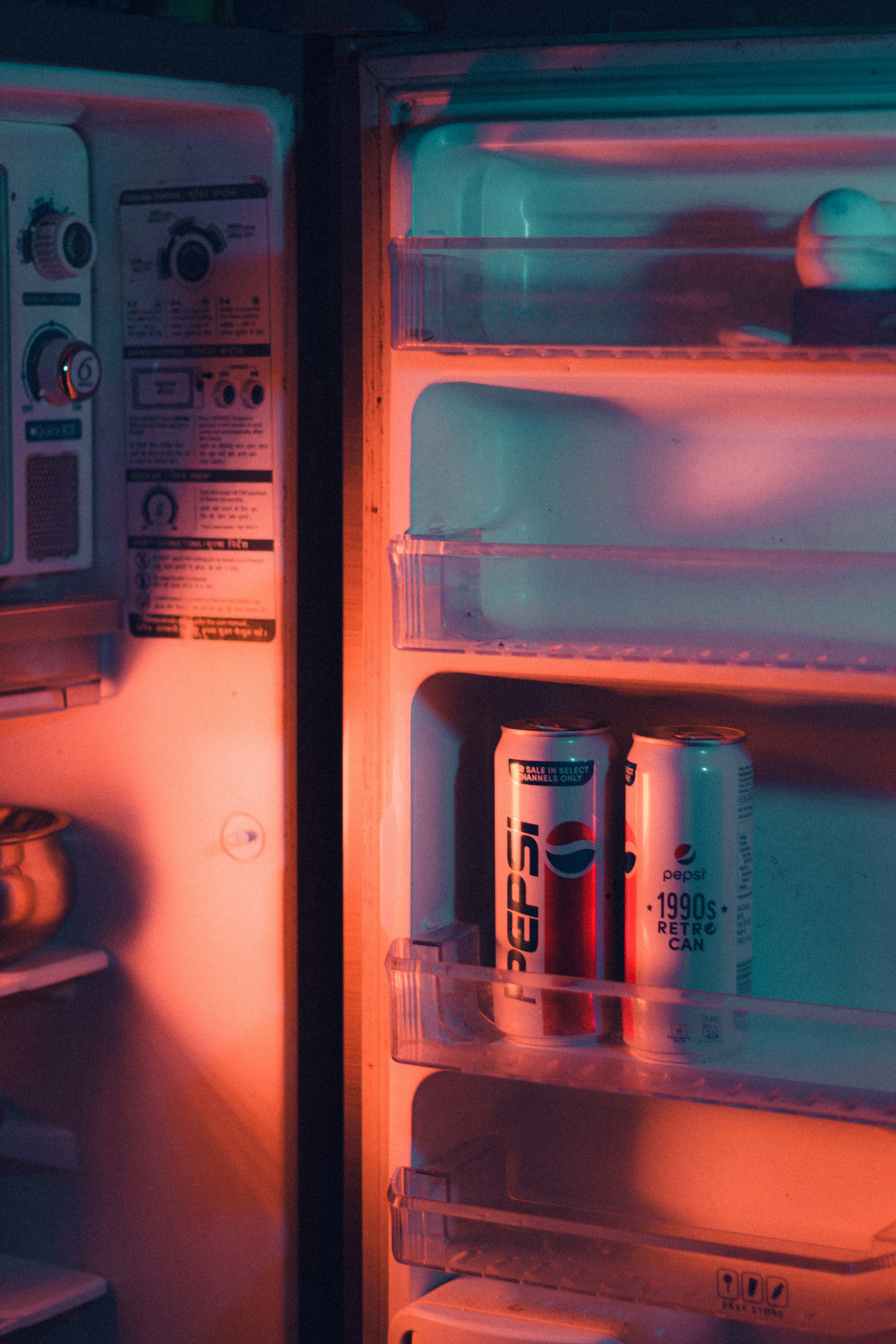 a refrigerator with two cans of soda inside of it