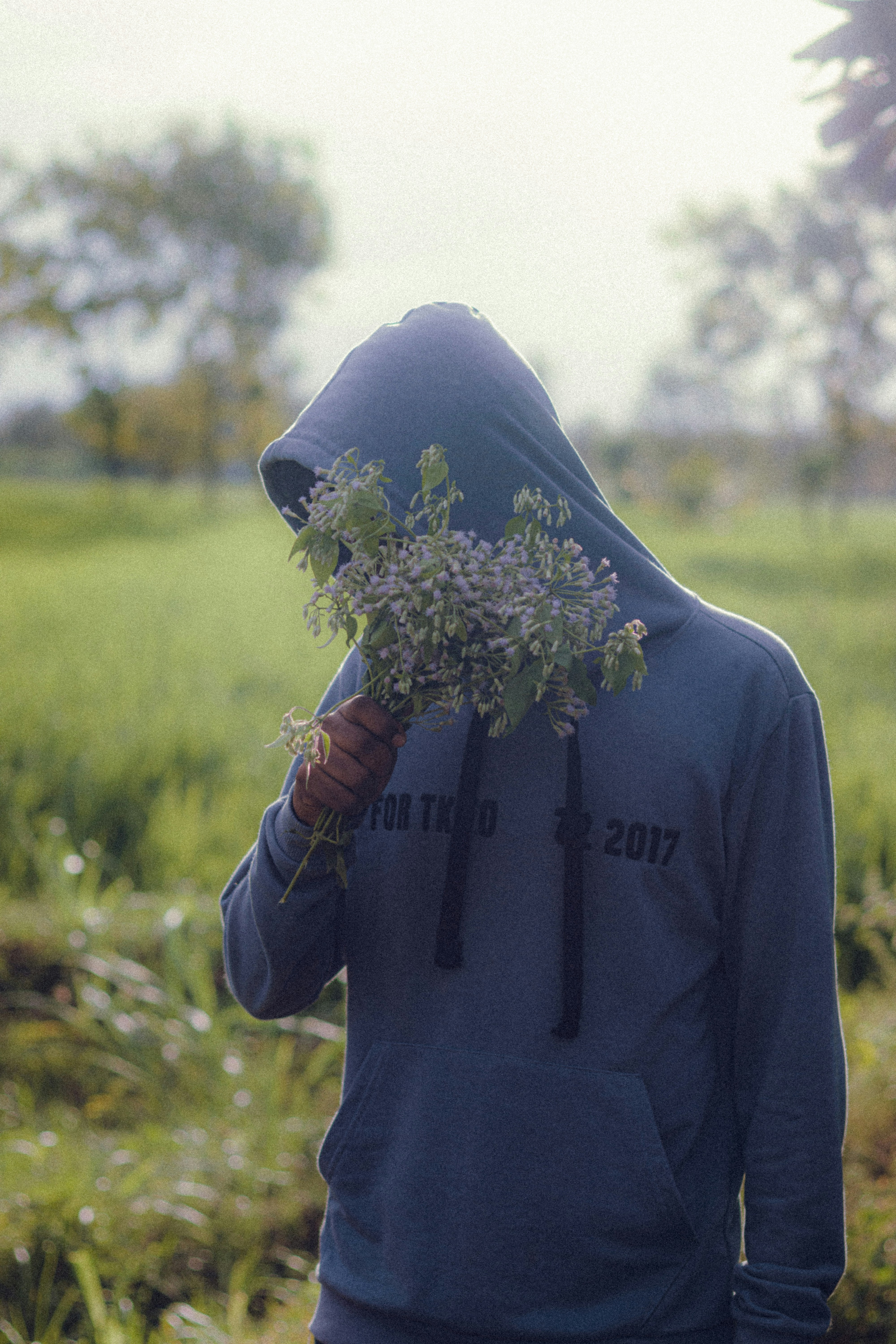 uma pessoa em um capuz segurando um ramo de flores