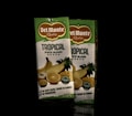 Two cartons of Del Monte Tropical Juice Blend are positioned side by side. The packaging is primarily green and white with images of tropical fruits such as pineapple, orange, and banana. The label highlights the absence of added sugars, colors, flavors, and preservatives.