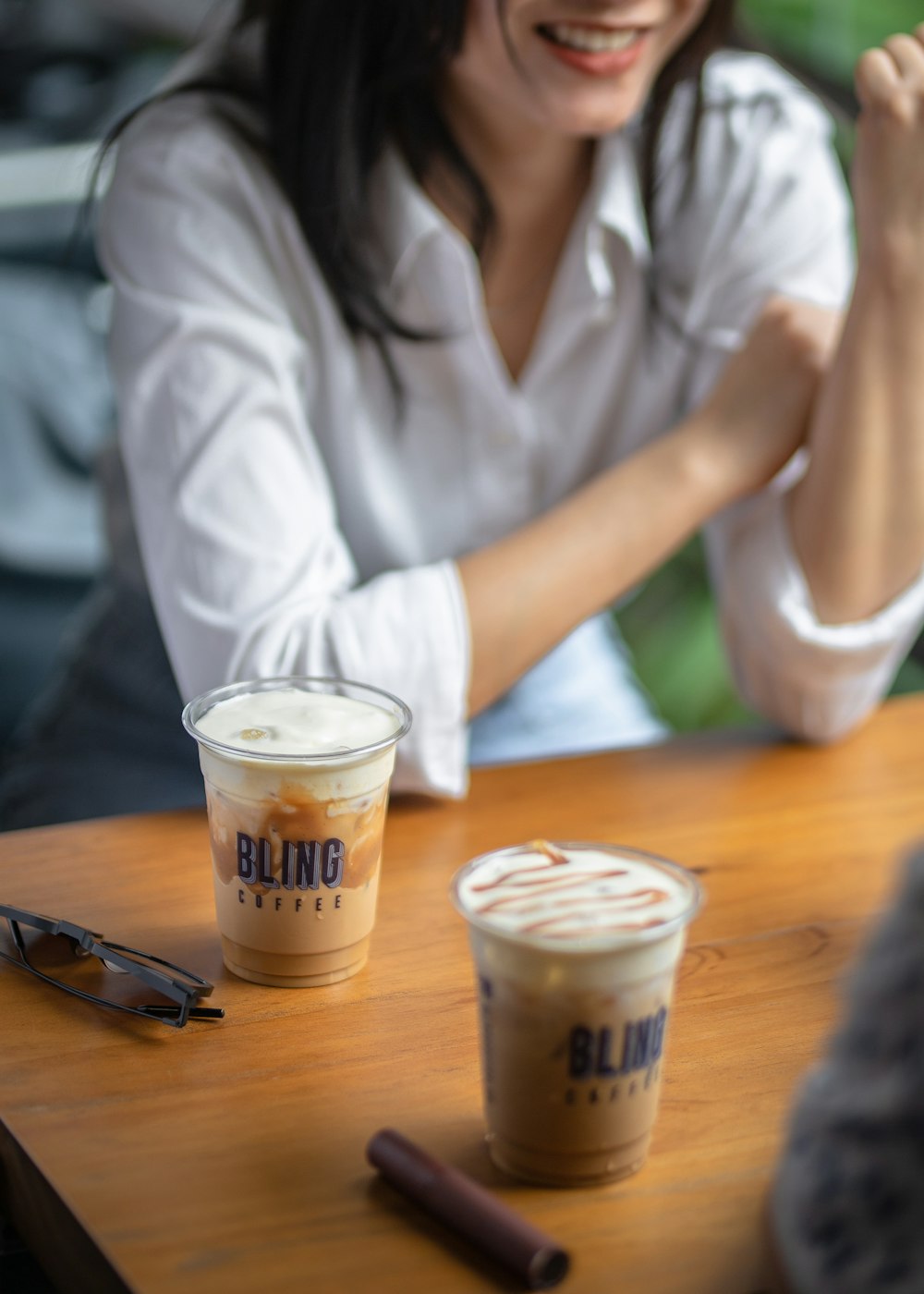 a woman sitting at a table with two cups of coffee