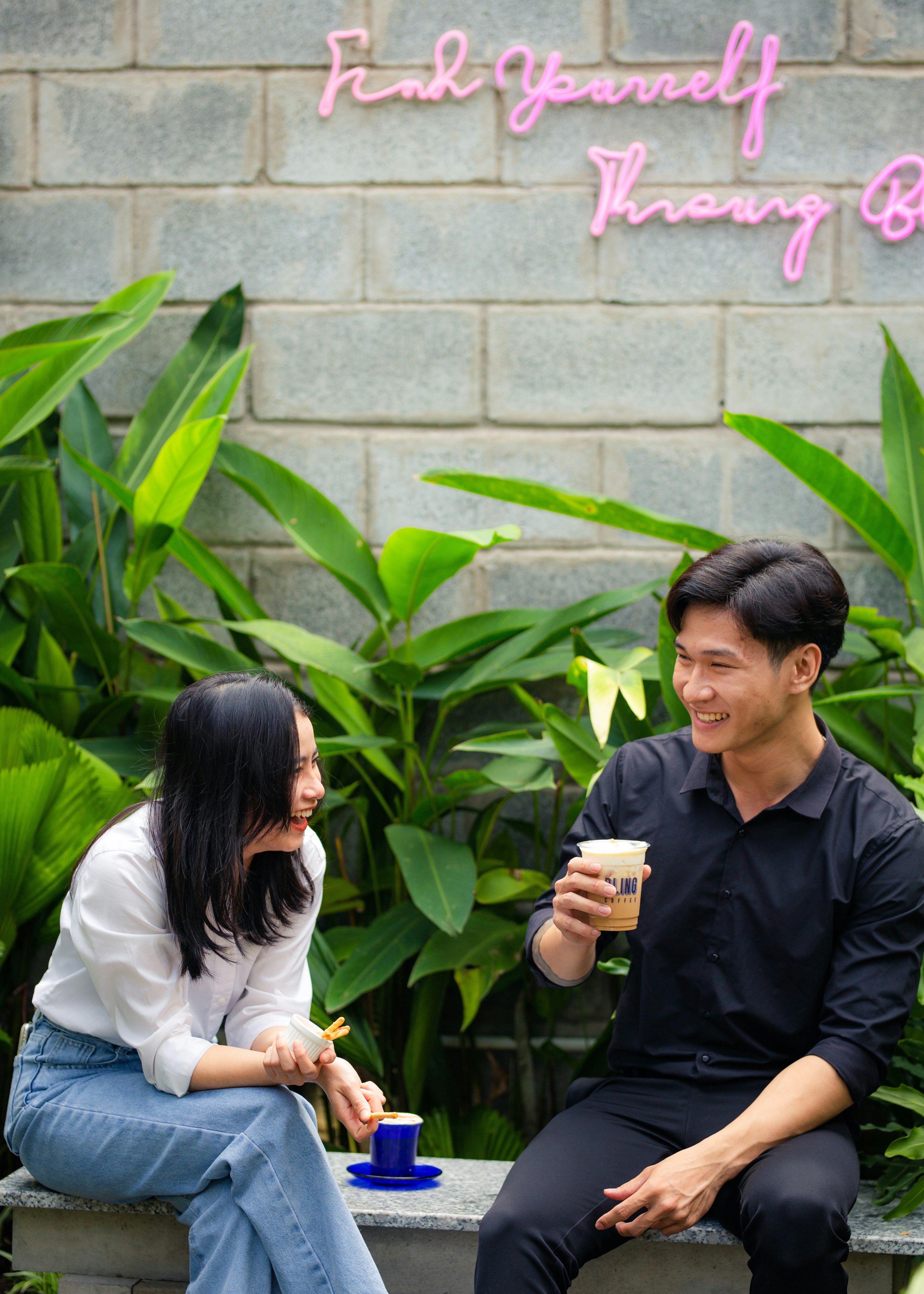 a man and a woman sitting on a bench drinking coffee