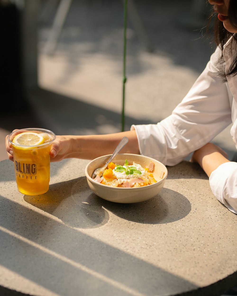 a woman sitting at a table with a bowl of food and a drink