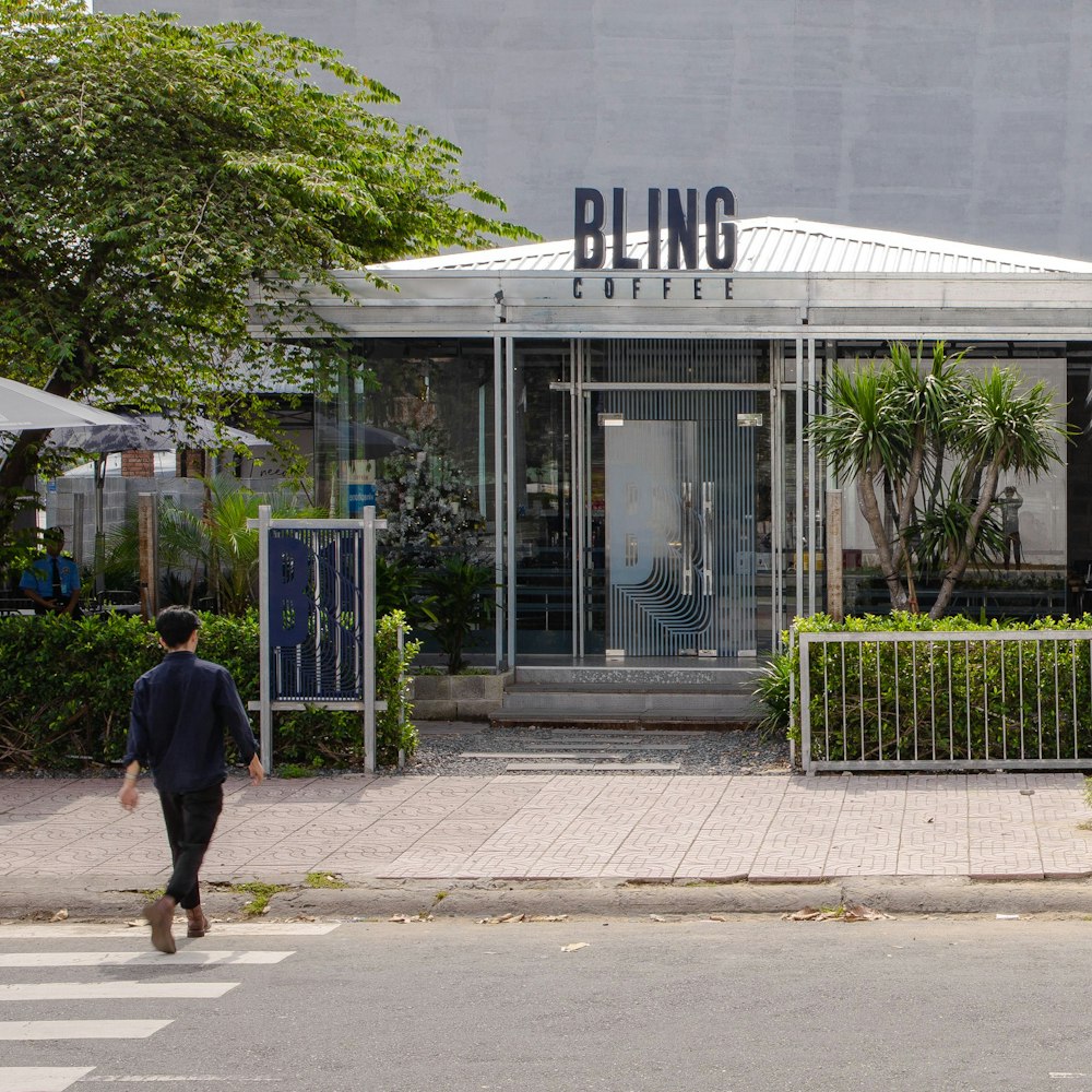 a man walking across a street in front of a building