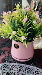 An elegant blush pink and green floral arrangement in a modern ceramic pot, placed near a window with natural light.