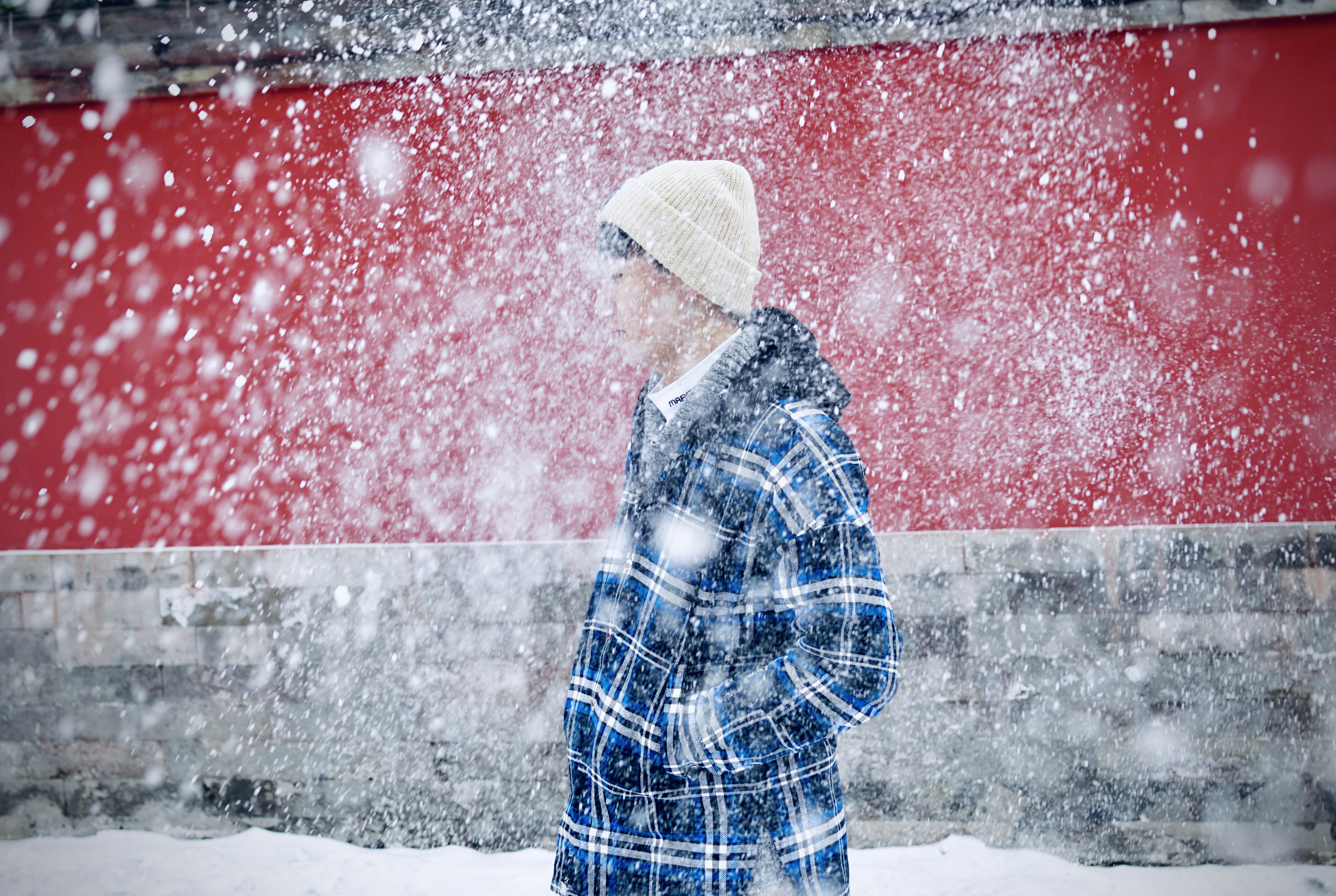 a person walking in the snow in front of a red building