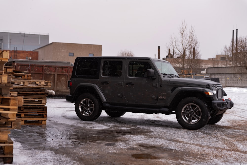 a jeep is parked in front of a pile of wood