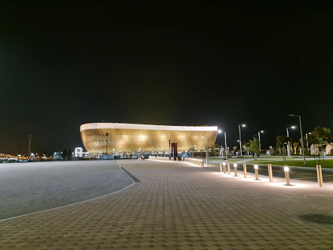 Golden-lit luxury commercial plaza at night with elegant landscaping.