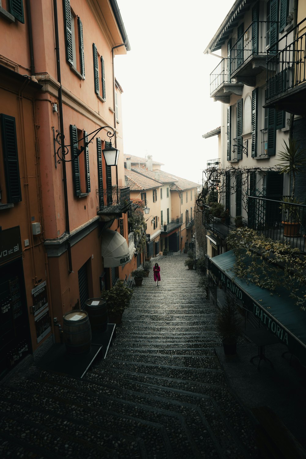 a woman walking down a street next to tall buildings