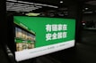 A large illuminated advertisement is displayed in an indoor setting, primarily showing a real estate company's branding. The sign features a green background with white text and includes an image of a building with the company's name, Lianjia, on it.