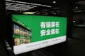 A large illuminated advertisement is displayed in an indoor setting, primarily showing a real estate company's branding. The sign features a green background with white text and includes an image of a building with the company's name, Lianjia, on it.