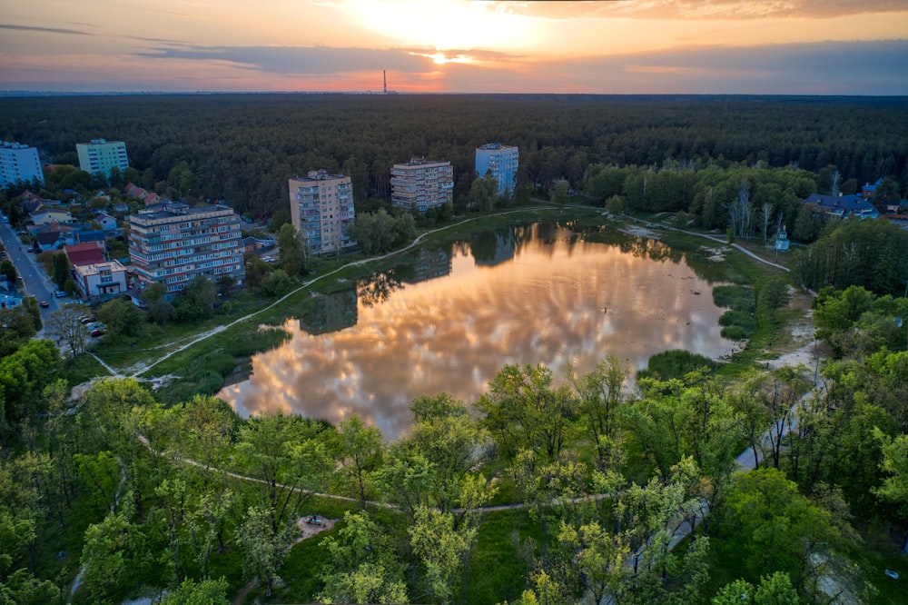 the sun is setting over a lake surrounded by trees