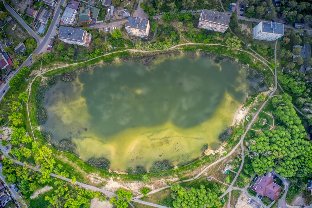 an aerial view of a green lake surrounded by trees