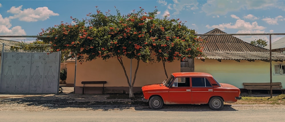 a red car parked in front of a tree