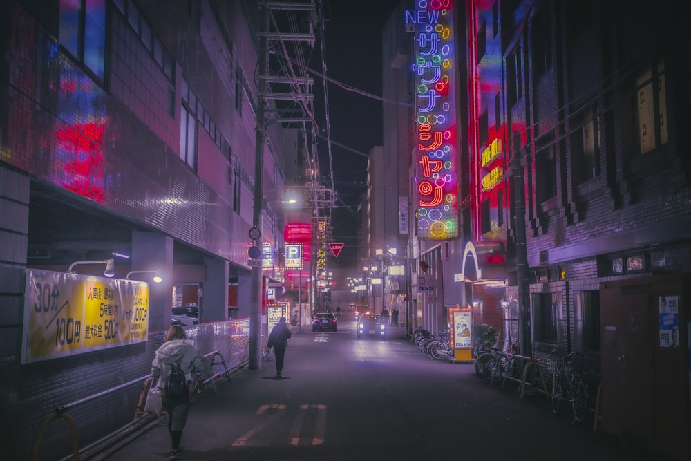 a couple of people walking down a street at night