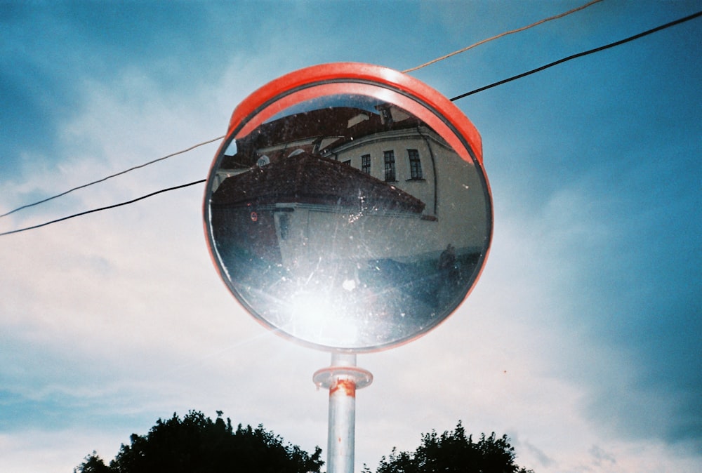 a mirror on a pole with a house in the reflection