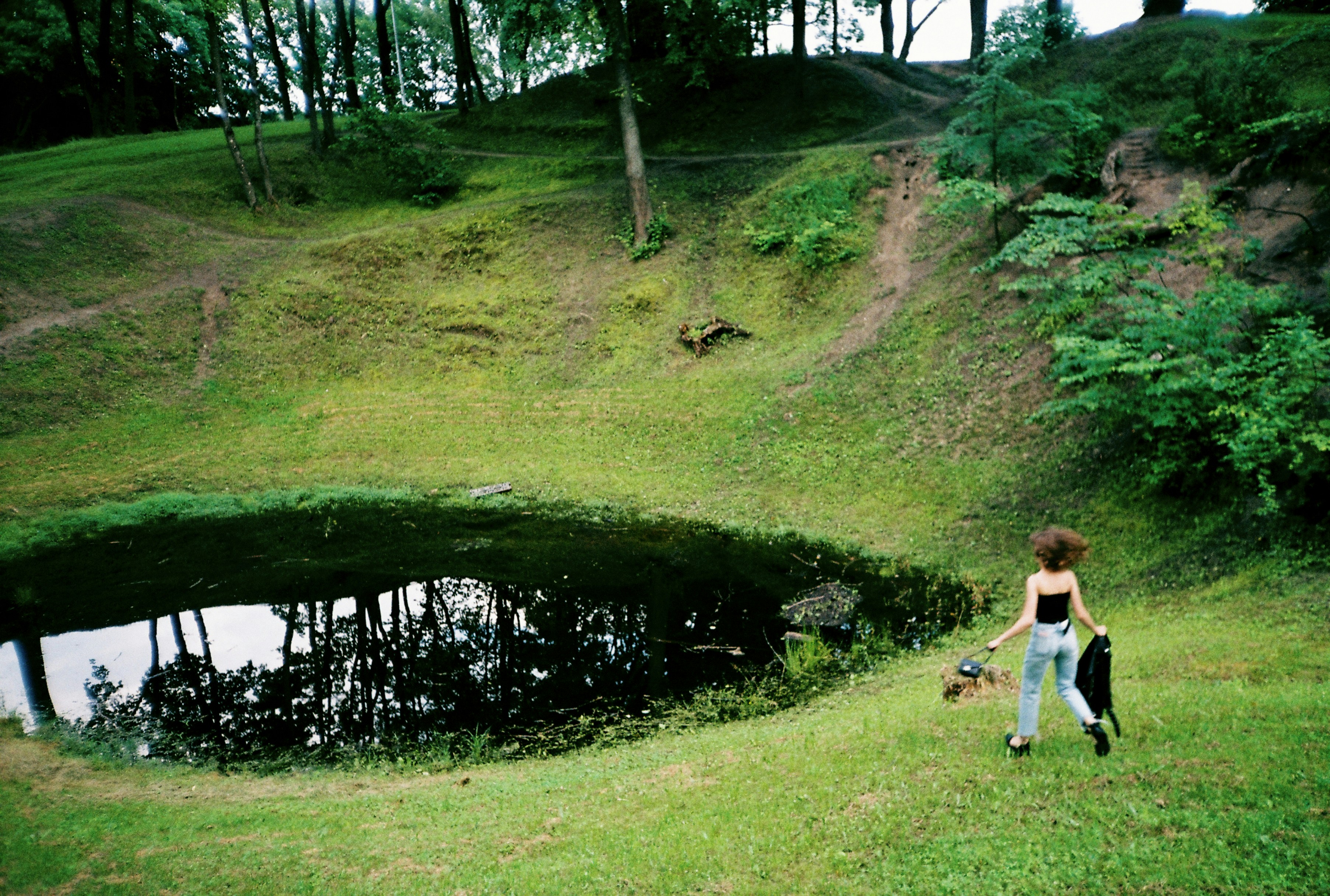 a woman walking a dog on a leash near a pond