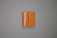A tan leather wallet is placed on a plain gray surface. The wallet features white stitching along the edges and has a flap closure.