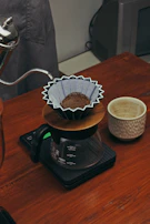 A morning coffee setup featuring an elegant pour-over kettle, a hand-thrown ceramic mug, and a newspaper.