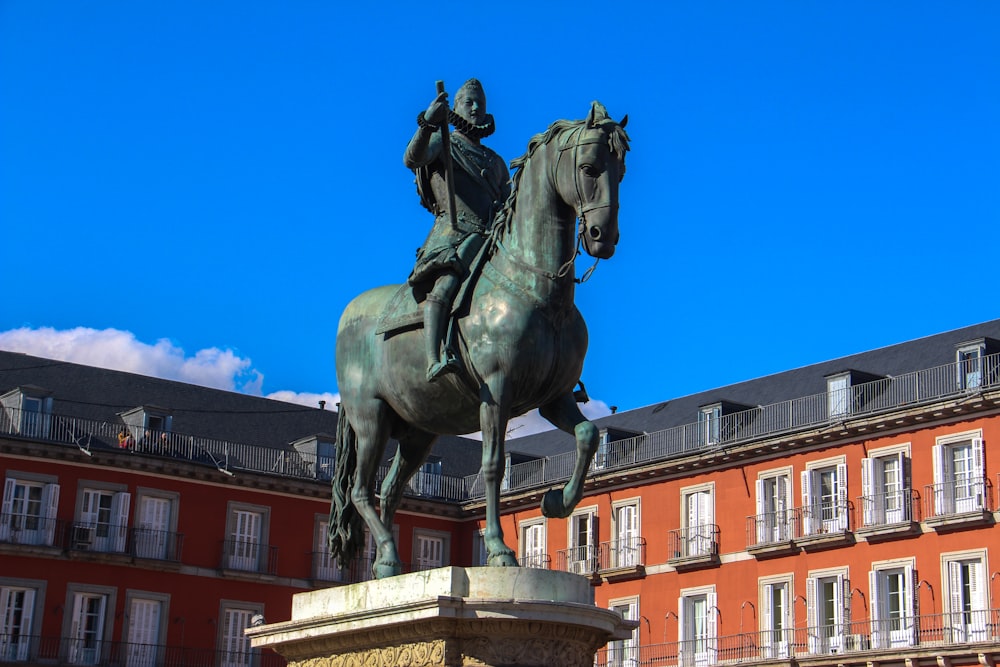 a statue of a man riding a horse in front of a building