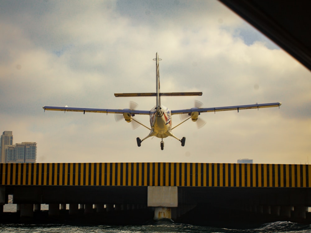 a small plane flying over a bridge over water