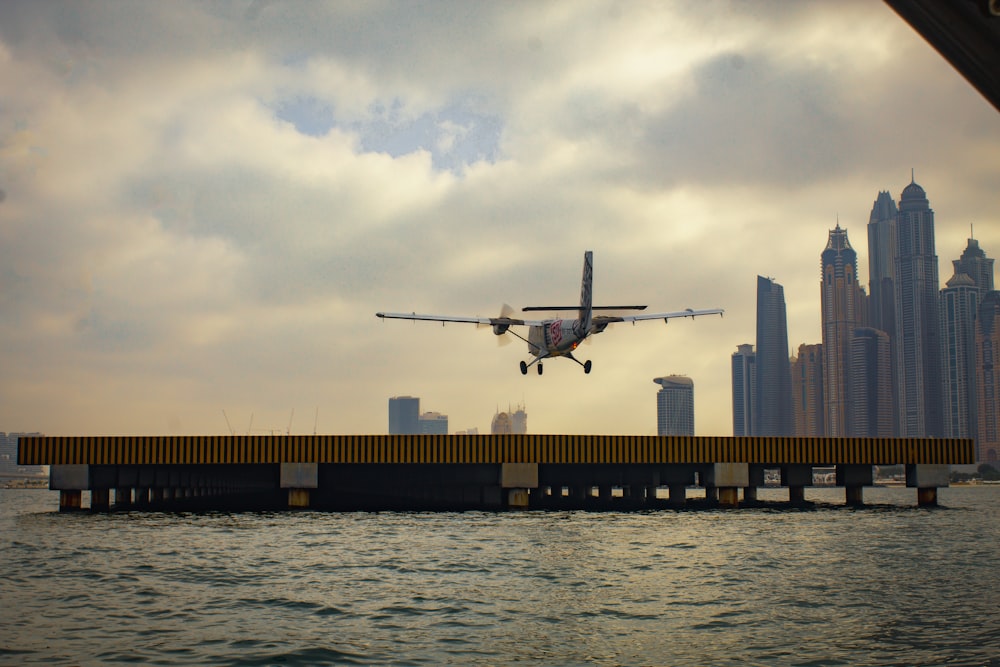 a plane is flying over the water with a city in the background