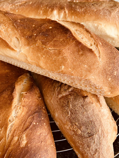 Freshly baked golden crusted bread loaves cooling on a wooden rack in a warm bakery setting