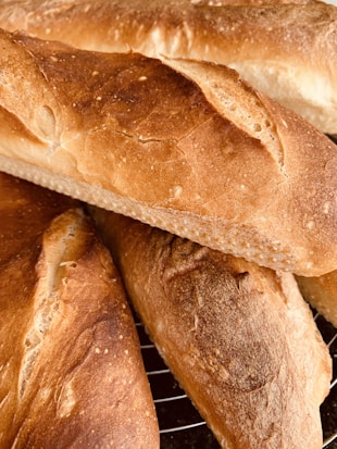 Freshly baked baguettes with a golden-brown crust and a rustic texture, resting on a cooling rack.