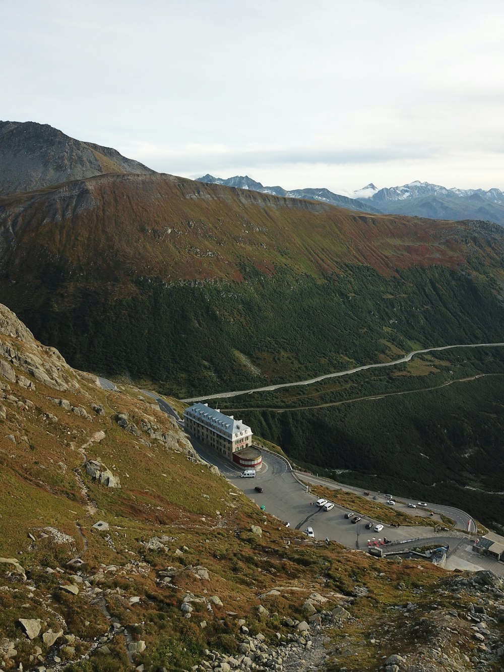 a truck driving down a road next to a lush green hillside